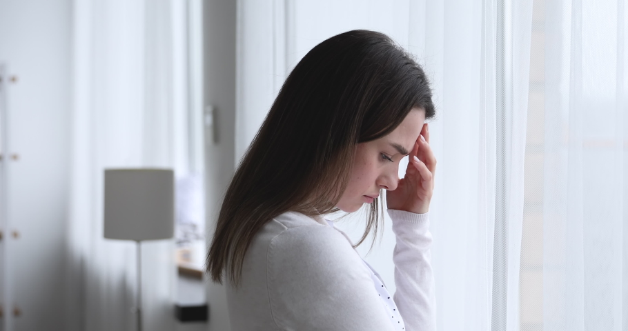 Head shot side view upset worried young brunette woman, looking out of window, thinking of problems. Depressed nervous millennial lady feeling doubtful about hard decision, mental stress concept. Royalty-Free Stock Footage #1054332320