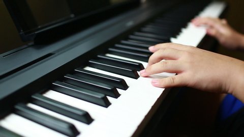 Selective focus to kid fingers and  piano key to play the piano. There are musical instrument for concert or learning music. Close up hand of child musician playing the piano on stage