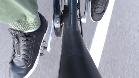 Cyclist twists pedals and riding electric bicycle with pedal power assistance. E bike gear close up from above. Exercising and healthy lifestyle leisure. Activity in the city.