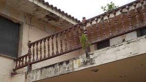 Wooden patterned balcony railing of an old abandoned house with fungus and moss on defective walls. Camera track - Powered by Shutterstock - Get 15% off with code: PIKWIZARD15