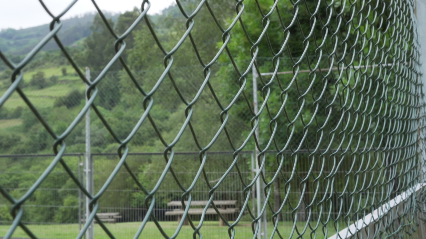 Close-up mesh iron fence in a green public wild park on a hill
