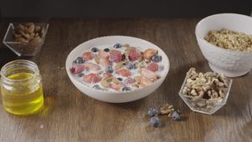 Slow video female's hand taking photos of freshly cooked healthy breakfast from granola and fresh fruits by smartphone above wooden table with ingredients. Slow motion, 2K video, 240fps, 1080p.