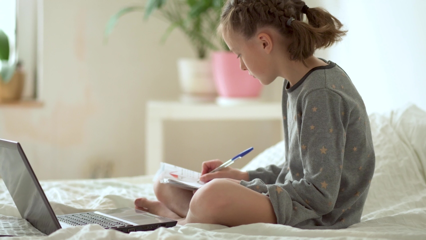 Cute child use laptop for education, online study. Girl has homework at home schooling. | Shutterstock HD Video #1054341335