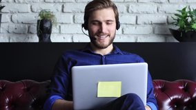 Confident man wearing headset speaking and watching business webinar training, listening to lecture. Call operator customer support service at home distance online.