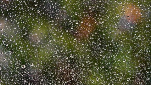 heavy rain falling on window.green bokeh in background from trees.spring rain  Video Stok