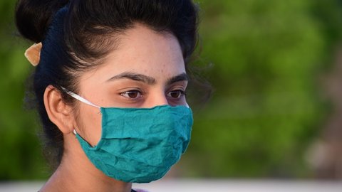 Woman wear face mask and look at park view.wearing virus mask, thinks about risk of epidemic disease, girl looks sadly at camera.shot in 4k resolution.