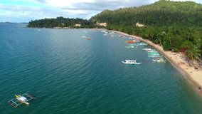 Top drone view of a traditional philippine boats on the surface of the azure water in the lagoon. Seascape with blue bay and boats. El Nido, Port Barton, Palawan. Summer and travel vacation concept.