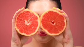 Healthy eating, diet. Beautiful healthy girl with slices of red grapefruit, food, cosmetics concept . Beauty young fashion woman plays with grapefruits, organic vegetables. Vegetarian. Slow motion 4K