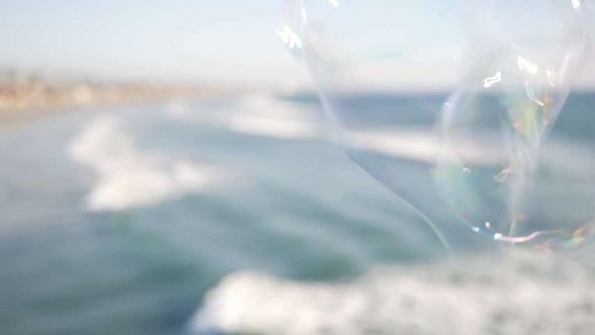 Soap bubbles on pier in California, blurred summertime seamless looped background. Creative romantic metaphor, concept of dreaming, happiness and magic. Abstract symbol of childhood, fantasy, freedom. Royalty-Free Stock Footage #1054348355