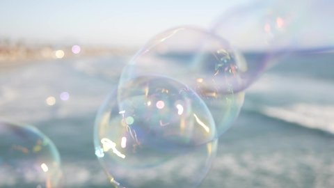 Soap bubbles on pier in California, blurred summertime seamless looped background. Creative romantic metaphor, concept of dreaming, happiness and magic. Abstract symbol of childhood, fantasy, freedom.