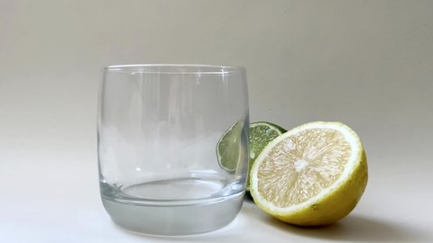 Sparkling cold mineral water is poured in glass with lemon, mint and lime. Fresh homemade lemonade. Refreshing gin and soda tonic cocktail. Mineral bubbles
in glass rise up. Healthy, dietary nutrition