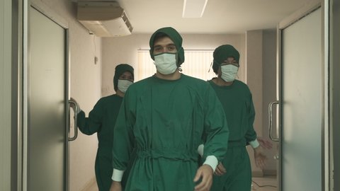 Group of doctors walking out the door from Hospital Operating Room with smile. Diverse Team, Multi ethnic of professional surgeons and nurses suture had successful surgery of covid19 patient operation