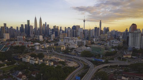 Malaysia Time lapse Sunset : Aerial city before dusk overlooking Kuala Lumpur city skyline and the Kuala Lumpur General Hospital with busy roundabout and streets. Prores UHD