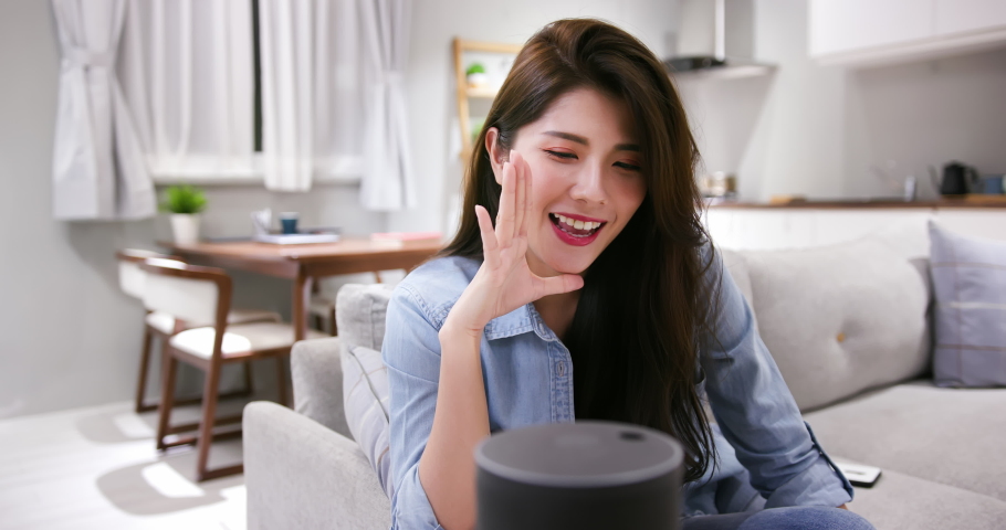 Smart speaker concept - Young Asian woman talks to voice assistant at home happily | Shutterstock HD Video #1054352798