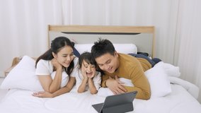 Happy Asian family watch online media using a digital tablet on the bedroom in home. Communication technology and lifestyle
