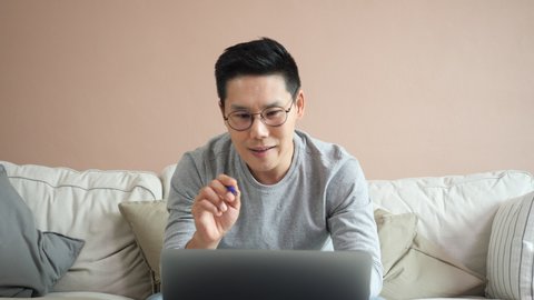 Asian businessman meeting online at home. Man working and conference online stay at home office. Handsome man present business analysis online in internet while being quarantine at home.