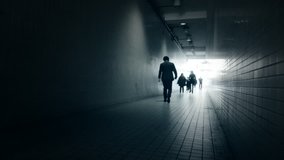 Slow motion video of business people walk in long dark tunnel with bright light in the end 