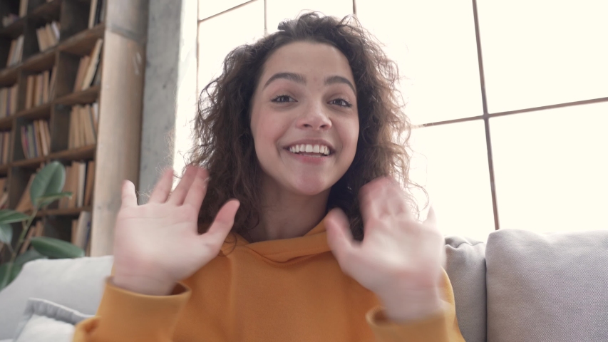Happy hispanic latin gen z teen girl blogger content maker smiling face wearing hoodie waving hand talking to cam online followers recording live vlog video blog, social media channel stream at home. Royalty-Free Stock Footage #1054360157