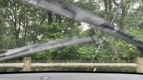 Video shot of the rain falling on the windshield of a car from inside the car.