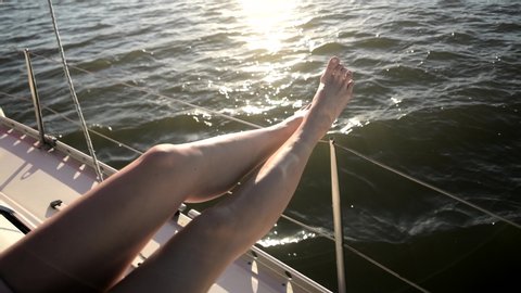 woman legs at sunset rays at luxury deck of sail yacht in ocean