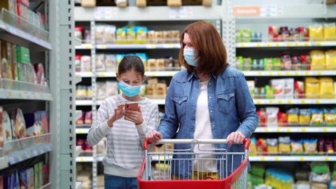 Mother and daughter buying sweets in supermarket during pandemic