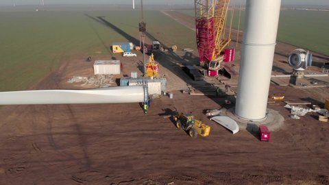 Building process of wind energy power tower mill, under construction. Transportation, installation of rotor blades. Green, clean, renewable energy. Aerial footage.