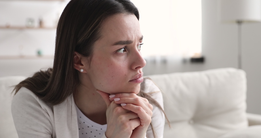 Head shot anxious young beautiful woman worrying about making doubtful hard decision. Close up nervous millennial girl waiting for news, thinking of problem solution, feeling jealous alone at home. | Shutterstock HD Video #1054366394