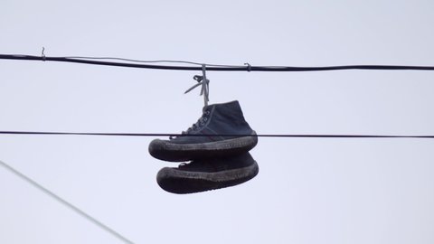 sneakers hanging on black wires against the sky