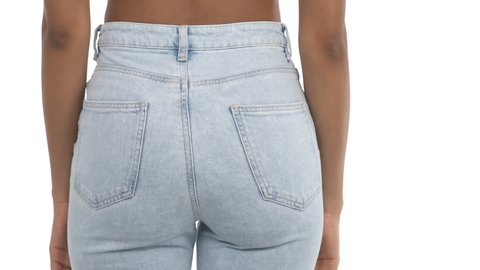 rear close-up view of unrecognizable African woman putting hands into back pockets of her blue skinny jeans. Isolated, on white background. beauty concept.