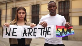 African American man and a caucasian woman are holding a poster that says we are the same and with LGBT symbols. Protest against racism and intolerance - Powered by Shutterstock - Get 15% off with code: PIKWIZARD15