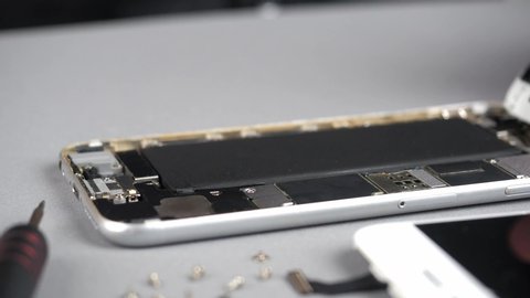 Locked down and close up of technician or engineer repairing or replace new parts of broken and damaged smartphone on desk. 4K resolution ultra HD