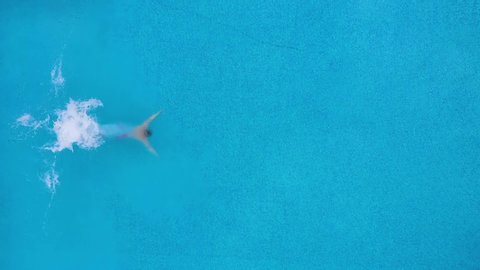 View from the top as a man dives into the pool and swims under the water