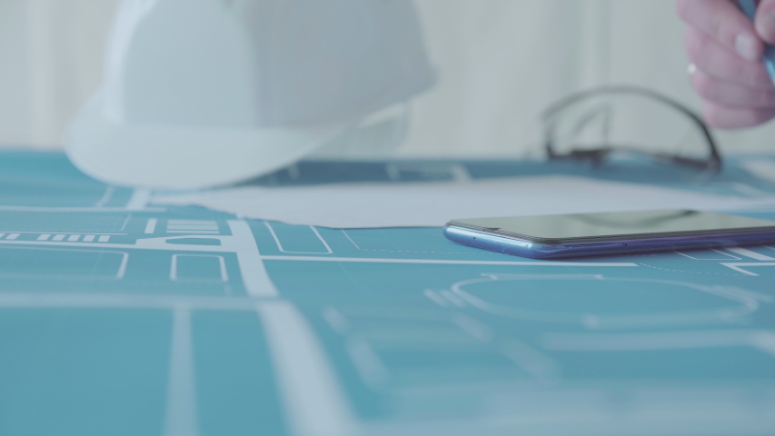 Young engineer-architect in a bright room works with drawings near the wall / technology, industry, business concept illustration: real estate, building, construction, architecture