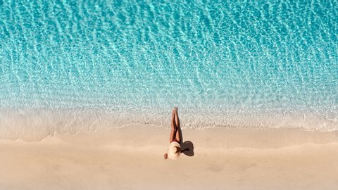 Beautiful young blonde woman at luxury hotel resort celebrating summer vacation. Aerial view of sand beach. Girl enjoying sunny day on travel holiday. Perfect for summer background. Tropical beach.