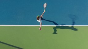 4K aerial top-down view of a young female sportsman during her practice. A close-up of a girl athlete serves the tennis ball. Young woman is hitting the ball with her tennis racket at sunset - Powered by Shutterstock - Get 15% off with code: PIKWIZARD15