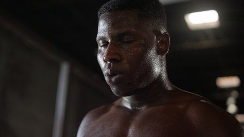 Close up shirtless African American boxer breathing deeply and resting