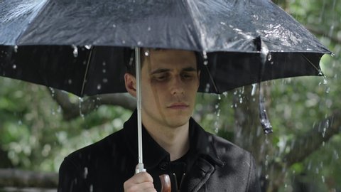 Sad man under umbrella at rain