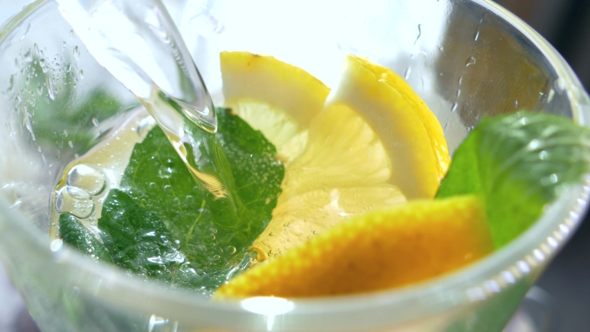 A refreshing soft drink. Mojito is poured into a glass close-up. Lemon mint and sparkling water with ice. Royalty-Free Stock Footage #1054377980