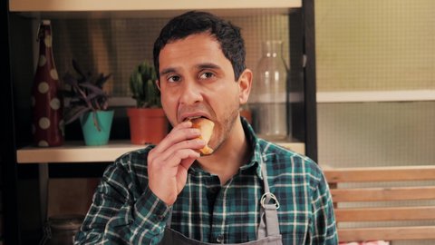 Happy spanish man eating empanadas pie on camera, portrait chef with traditional argentinian pie