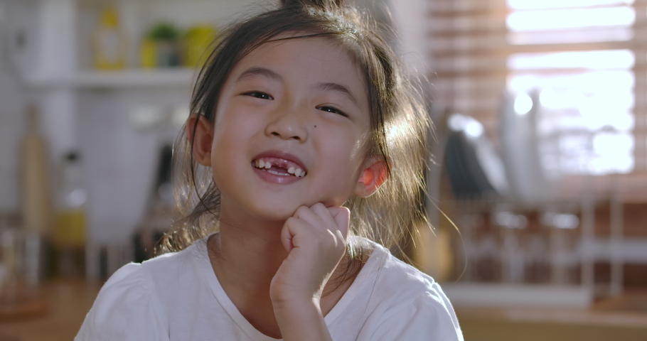 Close up portrait of Young asian little girl smiling with a toothless smile. Show no teeth. | Shutterstock HD Video #1054380374
