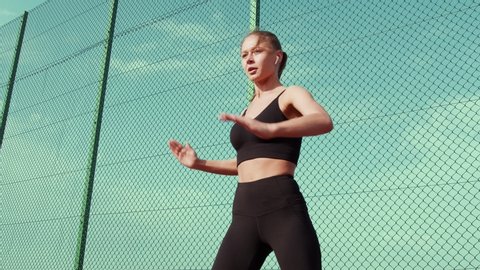 Close up of Fit Young Woman Athlete in Black Sportswear Training Hard, Doing Strength and Endurance Exercises. Attractive Girl with Headphones Doing Total Body Workout Outdoors. 스톡 비디오