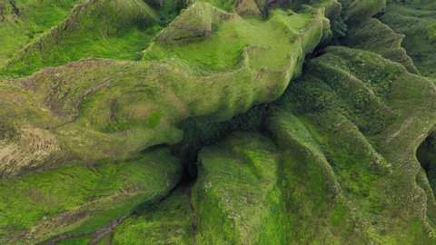 Na Pali Coast State park. Picturesque nature of mountainous terrain of Hawaii. Topdown aerial footage. Layered rocky surface with vertical cliffs and deep ravines covered with tropical greenery. 4K