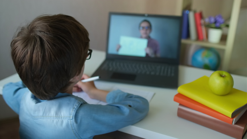 Online distance learning education lesson concept. Child Boy Kid schoolboy with teacher using tablet laptop computer for writing school homework, studying at home. Coronavirus COVID-19 quarantine, 4 K Royalty-Free Stock Footage #1054386212