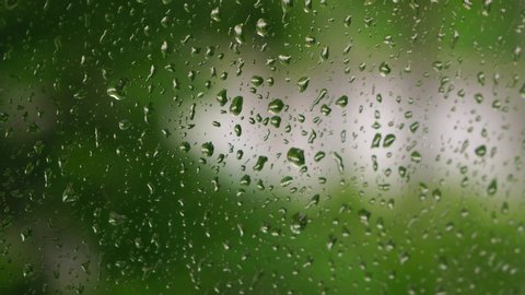 Close-up of water droplets on glass, Rain Rain, Go Away. Large rain drops strike a window pane during a summer shower