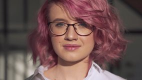 Happy young adult hipster gen z teen girl smiling face with pink hair and nose piercing wearing glasses looking at camera posing indoors in modern sunny home office. Head shot close up portrait. - Powered by Shutterstock - Get 15% off with code: PIKWIZARD15
