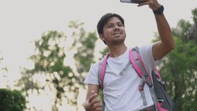 Young Asian man traveling backpacker video calling in the forest, Concept of nature tourism
