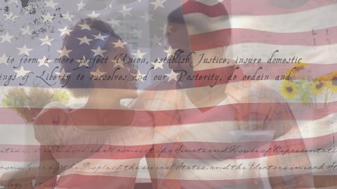 Animation of U.S. flag waving with U.S. Constitution text rolling over mixed race couple embracing. United States of America flag and holiday concept digital composition