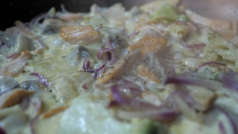 Red salmon fish, violet onion, broccoli is frying under creamy sauce on the pan, close up view. Delicious fish fry meal. Appetizing seafood dish, icelandic, norwegian, canadian dish.