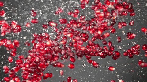 Super Slow Motion Shot of Fresh Pomegranate Seeds and Water Side Collision on Grey Background at 1000fps.