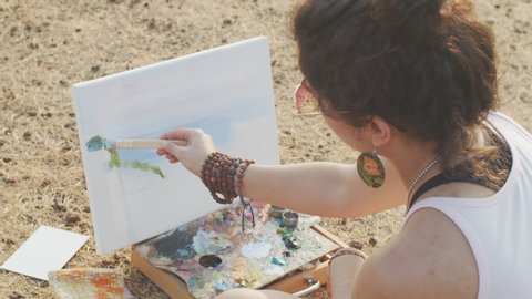 Side portrait of female artist painting colorful canvas outdoors on fresh air. Young woman relaxing with art equipment tools creating artwork slow motion. Art process creative lifestyle concept : vidéo de stock